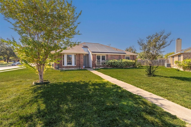 ranch-style house featuring cooling unit, a front yard, and solar panels