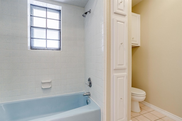 bathroom featuring tile patterned flooring, tiled shower / bath combo, and toilet