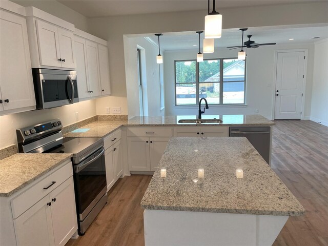 kitchen featuring stainless steel appliances, hanging light fixtures, a kitchen island, and sink