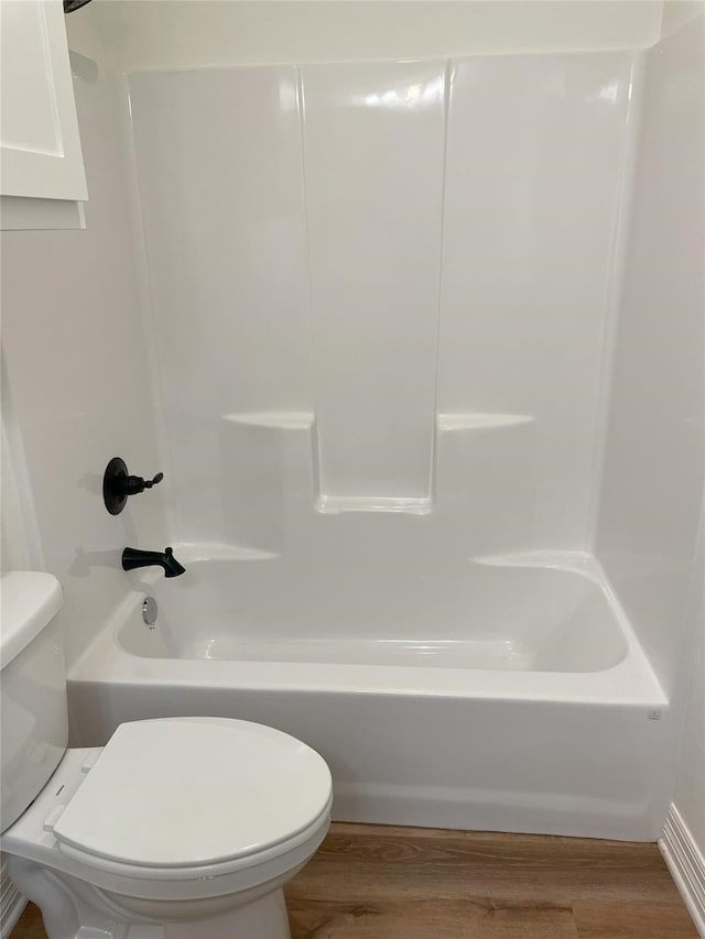 bathroom with wood-type flooring, toilet, and washtub / shower combination