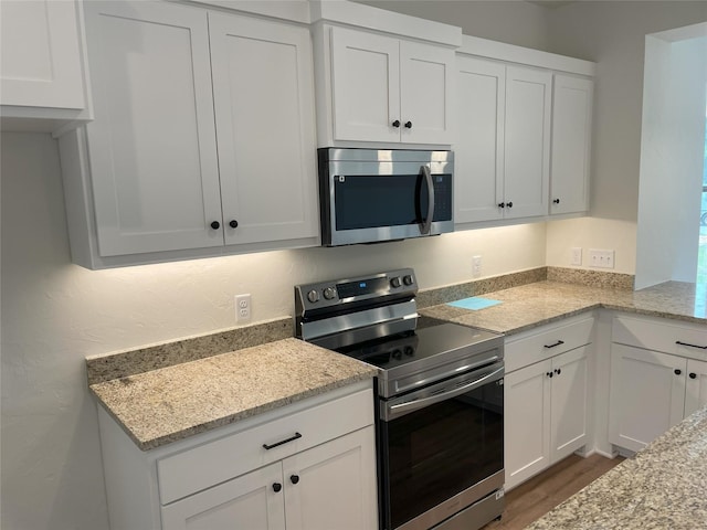 kitchen featuring stainless steel appliances, white cabinets, dark hardwood / wood-style flooring, and light stone counters