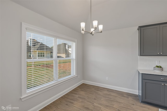 unfurnished dining area with wood-type flooring and an inviting chandelier