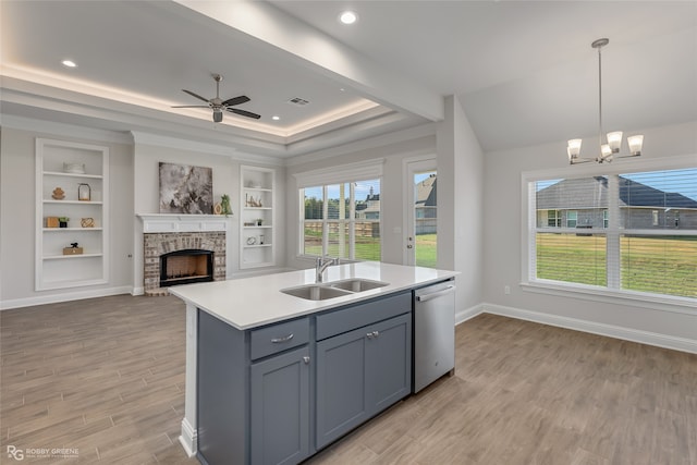 kitchen with a center island with sink, sink, stainless steel dishwasher, decorative light fixtures, and light hardwood / wood-style floors