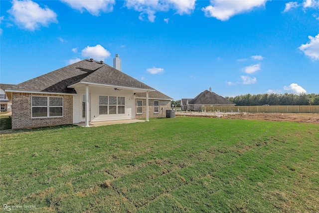 back of property with ceiling fan, cooling unit, a yard, and a patio