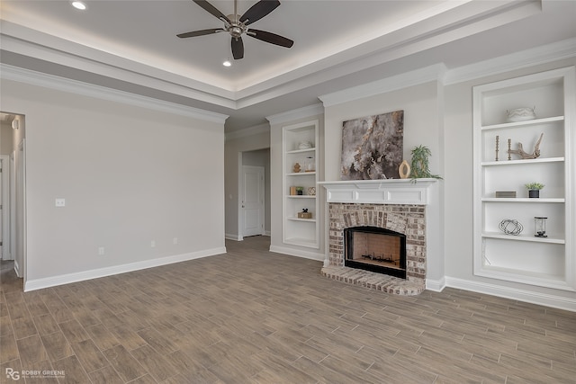 unfurnished living room featuring a fireplace, ceiling fan, built in features, and wood-type flooring