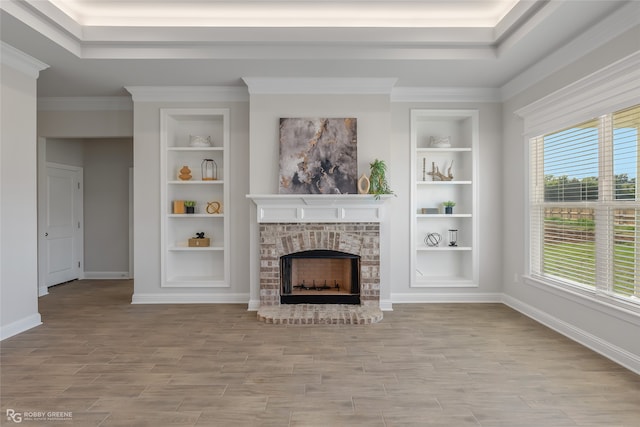 unfurnished living room with a wealth of natural light, crown molding, built in features, and a brick fireplace