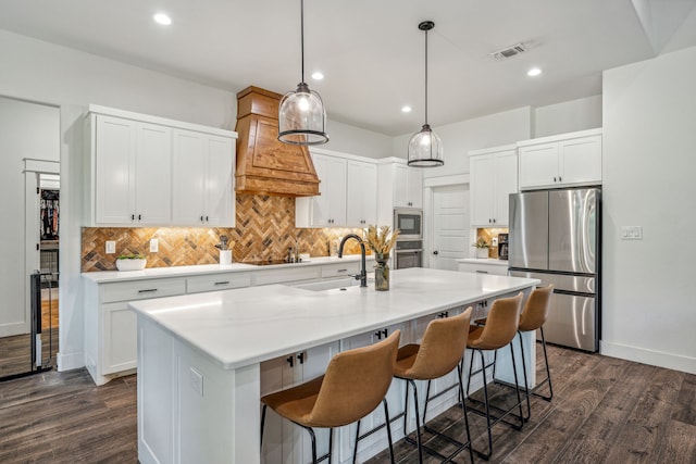 kitchen featuring an island with sink, appliances with stainless steel finishes, dark wood-type flooring, and white cabinetry