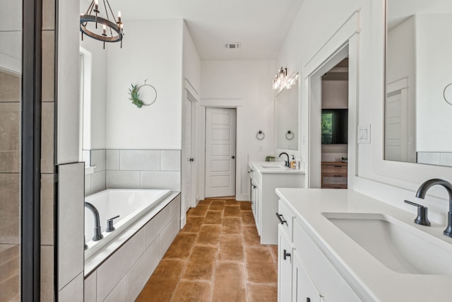 bathroom featuring a relaxing tiled tub, vanity, a chandelier, and tile patterned floors