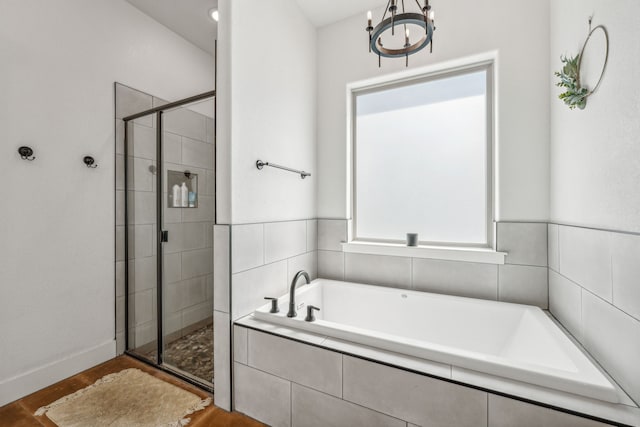 bathroom featuring independent shower and bath, hardwood / wood-style flooring, and a notable chandelier