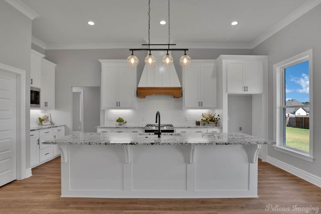 kitchen featuring white cabinets, an island with sink, and light wood-type flooring