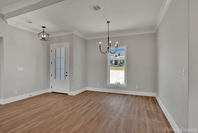 unfurnished dining area featuring wood-type flooring, crown molding, and a notable chandelier