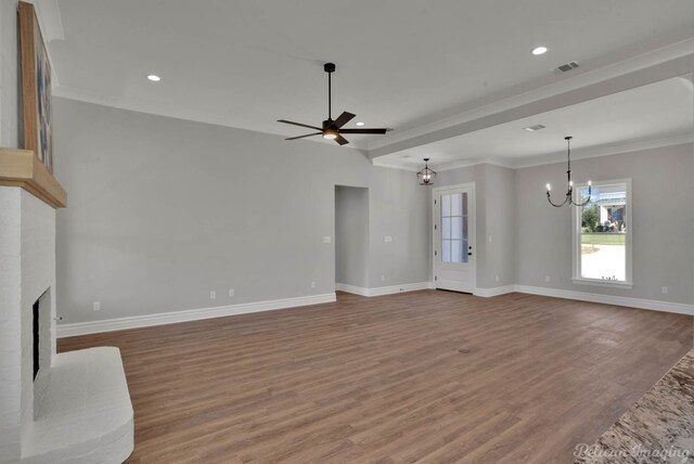 unfurnished living room with hardwood / wood-style flooring, ceiling fan with notable chandelier, ornamental molding, and a brick fireplace