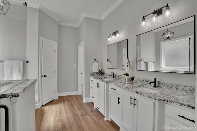 bathroom featuring a chandelier, crown molding, vanity, and wood-type flooring