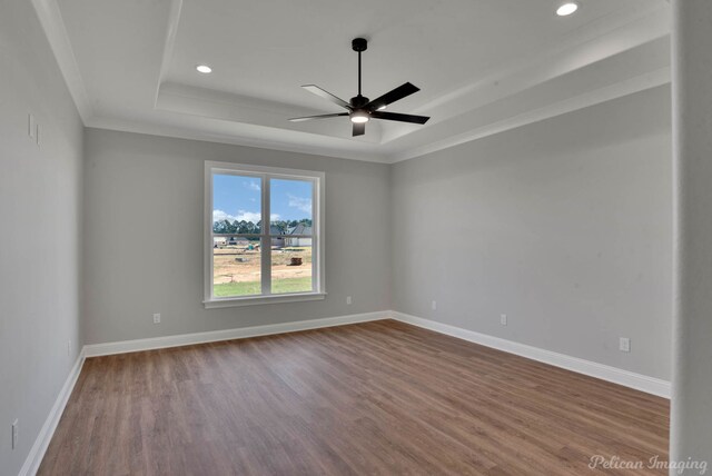 spare room featuring a tray ceiling, ceiling fan, wood-type flooring, and ornamental molding