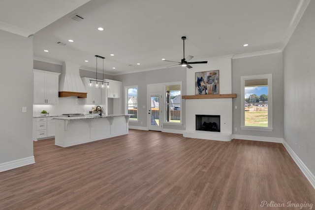 unfurnished living room featuring a fireplace, wood-type flooring, ceiling fan, and crown molding