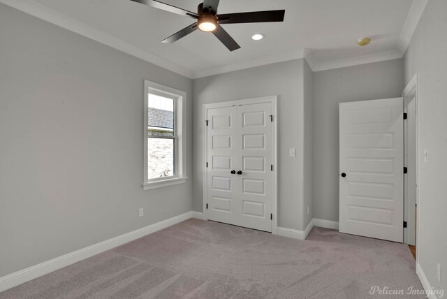 unfurnished bedroom with a closet, light colored carpet, ceiling fan, and crown molding