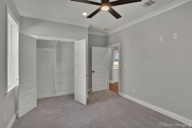 unfurnished bedroom with a closet, light colored carpet, ceiling fan, and ornamental molding