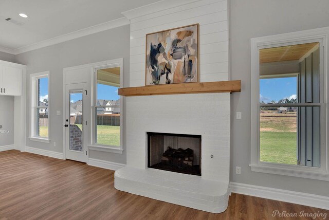 unfurnished living room with crown molding, wood-type flooring, and a brick fireplace