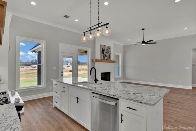 kitchen with dishwasher, sink, a large fireplace, light hardwood / wood-style floors, and white cabinetry