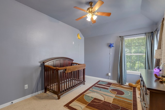 carpeted bedroom with ceiling fan, a nursery area, and lofted ceiling