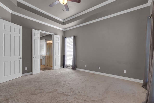 unfurnished bedroom with a tray ceiling, light carpet, crown molding, and ceiling fan