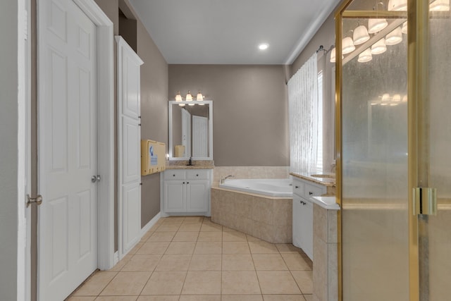 bathroom with tiled tub, vanity, and tile patterned floors