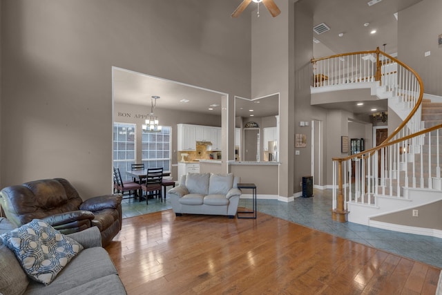 living room featuring a towering ceiling, hardwood / wood-style floors, and ceiling fan with notable chandelier