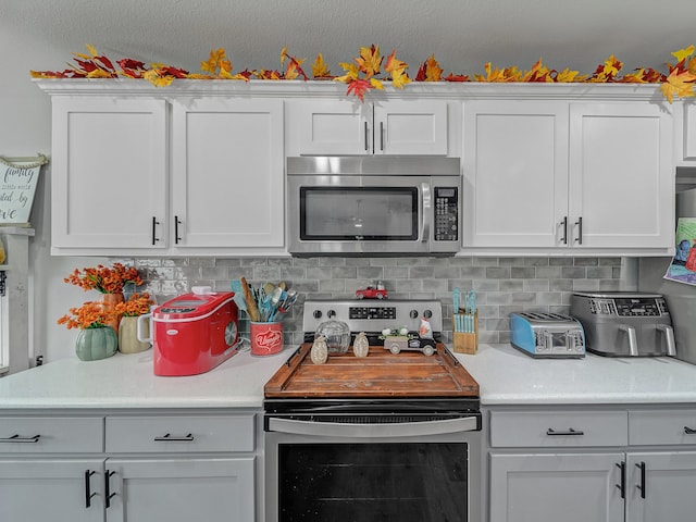 kitchen with appliances with stainless steel finishes, backsplash, and white cabinetry