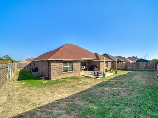 rear view of house with a yard, cooling unit, and a patio area