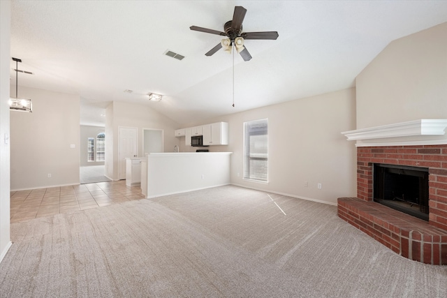 unfurnished living room featuring lofted ceiling, a fireplace, ceiling fan, and light carpet