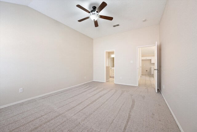 unfurnished bedroom featuring ceiling fan, light colored carpet, connected bathroom, and vaulted ceiling