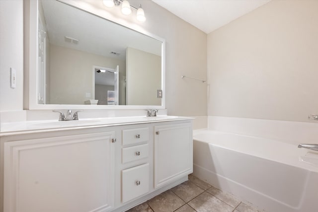 bathroom with tile patterned floors, a tub, and vanity