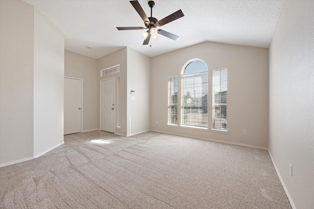 unfurnished room with a textured ceiling, ceiling fan, vaulted ceiling, and light colored carpet