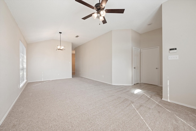 unfurnished room with lofted ceiling, ceiling fan with notable chandelier, and light carpet