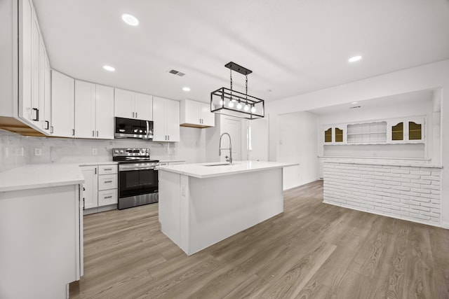 kitchen featuring white cabinets, appliances with stainless steel finishes, sink, and a kitchen island with sink