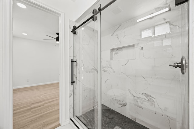 bathroom with hardwood / wood-style flooring, ceiling fan, and a shower with shower door