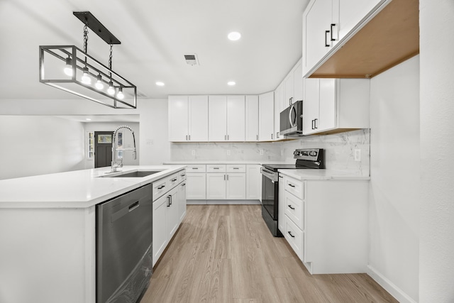 kitchen featuring light hardwood / wood-style floors, pendant lighting, sink, stainless steel appliances, and white cabinetry