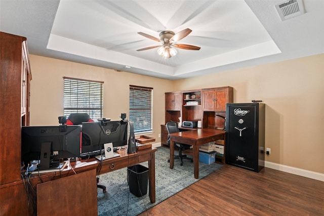 office space featuring dark wood-type flooring, ceiling fan, and a raised ceiling