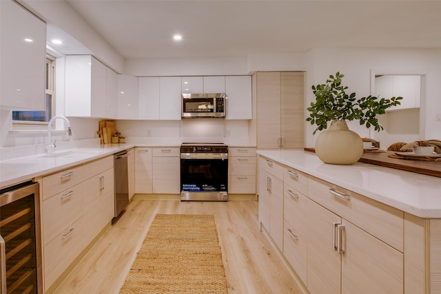 kitchen featuring stainless steel appliances, light hardwood / wood-style floors, wine cooler, and sink