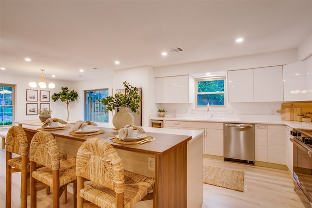 kitchen with light hardwood / wood-style flooring, sink, stainless steel appliances, white cabinets, and a center island