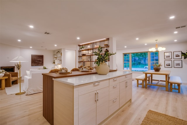 kitchen with a center island, decorative light fixtures, an inviting chandelier, and light wood-type flooring