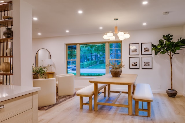 dining area with light hardwood / wood-style floors and a notable chandelier