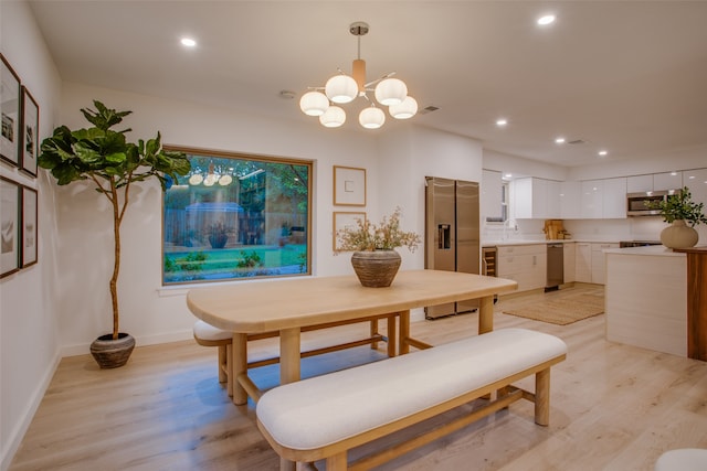 dining area featuring sink, an inviting chandelier, and light hardwood / wood-style flooring