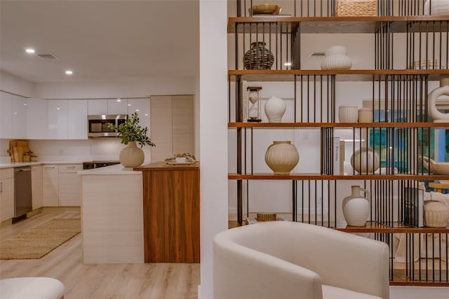 interior space with stainless steel appliances, white cabinets, and light hardwood / wood-style flooring