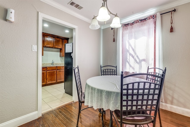 dining area featuring a notable chandelier, ornamental molding, light hardwood / wood-style flooring, and sink