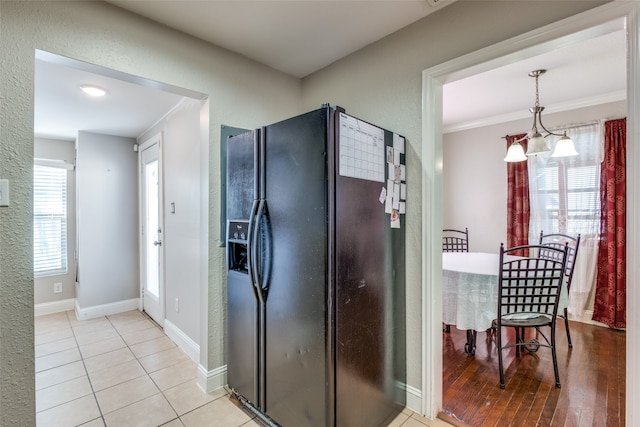 kitchen with light hardwood / wood-style flooring, decorative light fixtures, a notable chandelier, black fridge, and ornamental molding