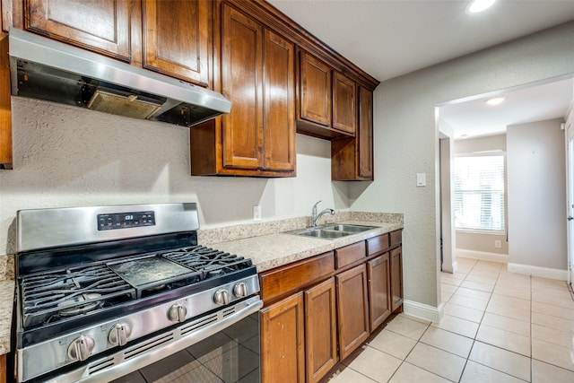 kitchen featuring stainless steel gas range oven, sink, light tile patterned flooring, and range hood