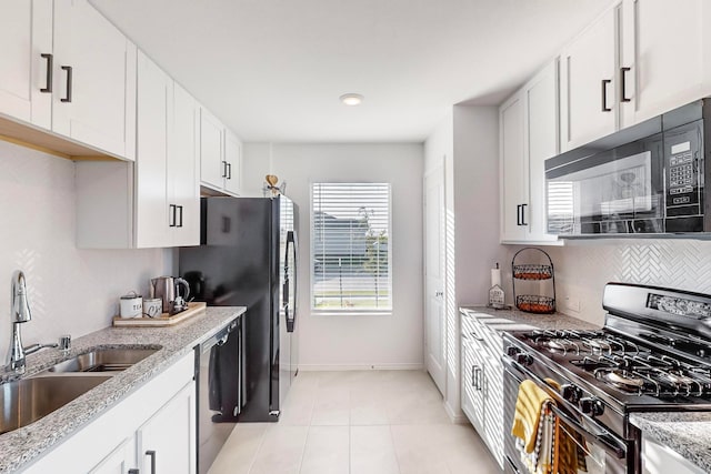 kitchen featuring light stone countertops, stainless steel appliances, sink, white cabinetry, and light tile patterned floors