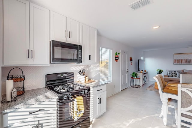 kitchen featuring light stone counters, light tile patterned flooring, backsplash, white cabinetry, and black appliances