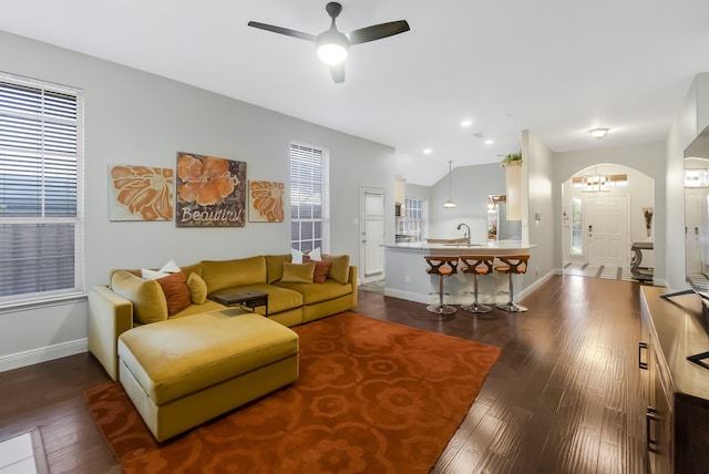 living room featuring ceiling fan with notable chandelier, dark hardwood / wood-style flooring, lofted ceiling, and sink